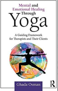 The image is of the white front cover of a book with at the top of the cover the title Mental and Emotional Healing through Yoga: A Guiding Framework for Therapist and their Clients in black and purple writing, in the middle of the cover a black silhouette of a person in Warrior II pose standing with the left knee bent and the arms outstretched to the sides with many colors in a circle right around the silhouette, and with the name Ghada Osman at the bottom of the cover